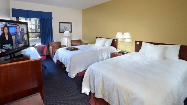 A hotel room with two queen size beds facing a TV